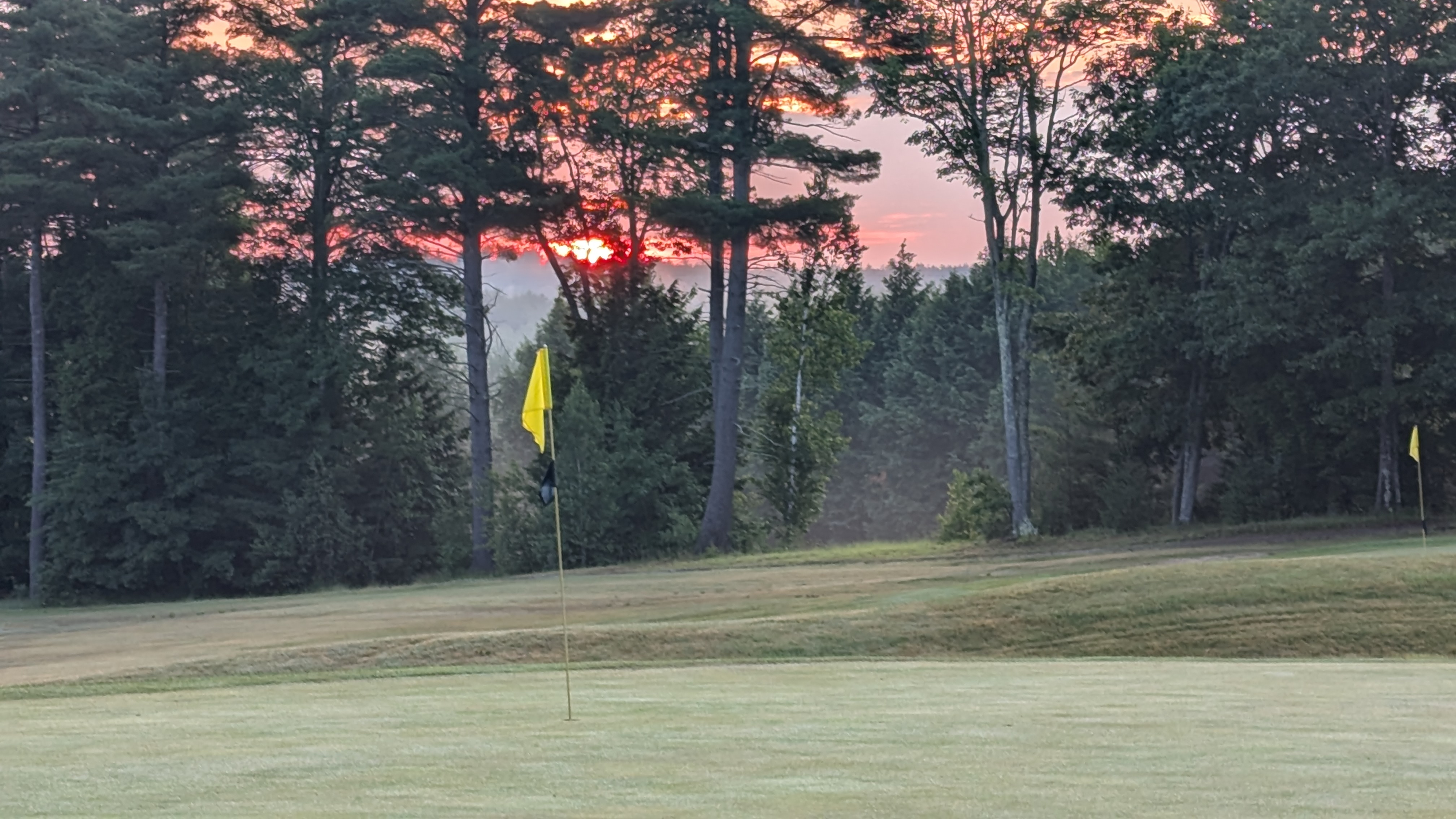 Flag on golf course at sunset